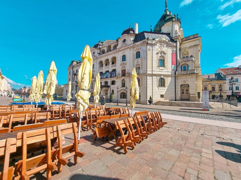 a group of benches and umbrellas in front of a building at Hlavna Apartment Kosice in Košice
