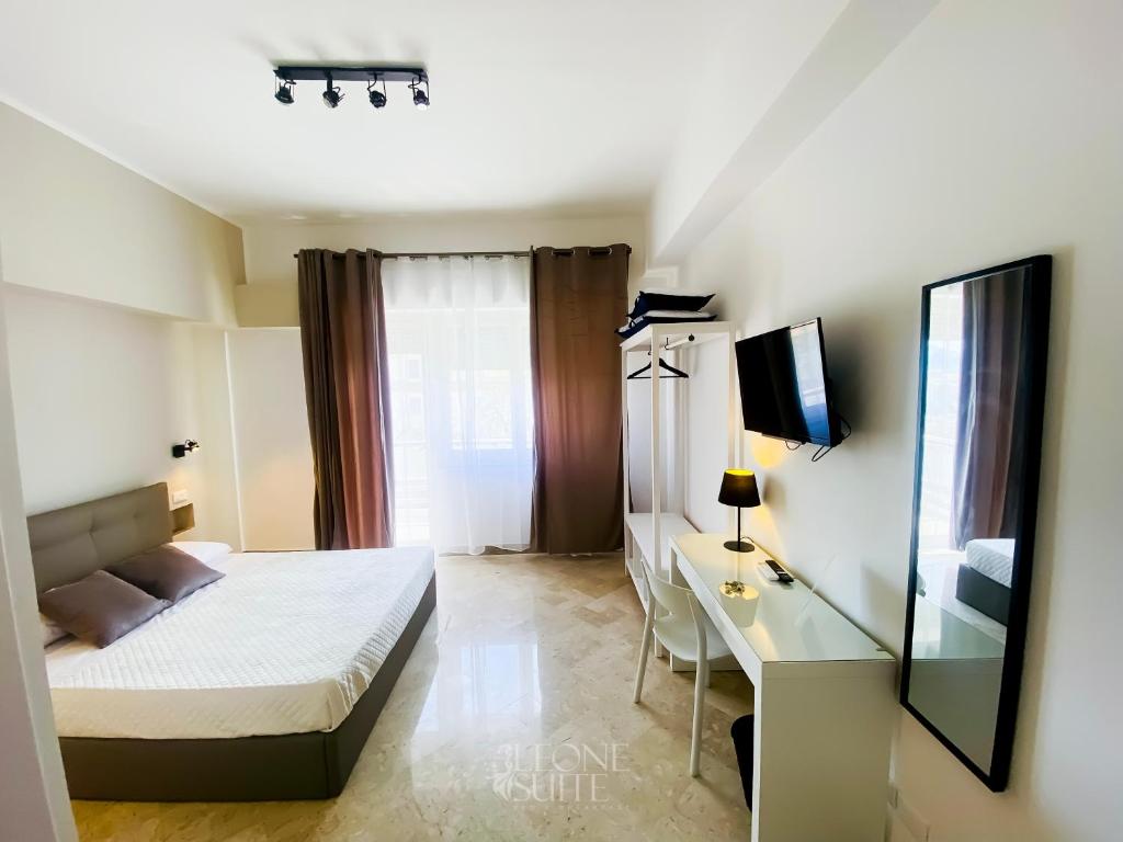 Dormitorio con cama, escritorio y TV en Leone Suite B&B & Restaurant, en Palermo