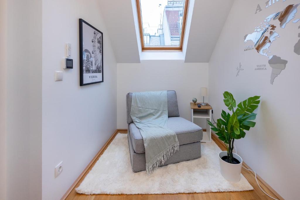 uma sala de estar com uma cadeira e uma planta em Rooftop cozy apartment near innerstadt with AC em Viena