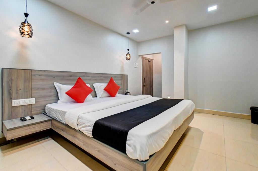 1 dormitorio con 1 cama grande con almohadas rojas en Hotel Vikrant, en Pune