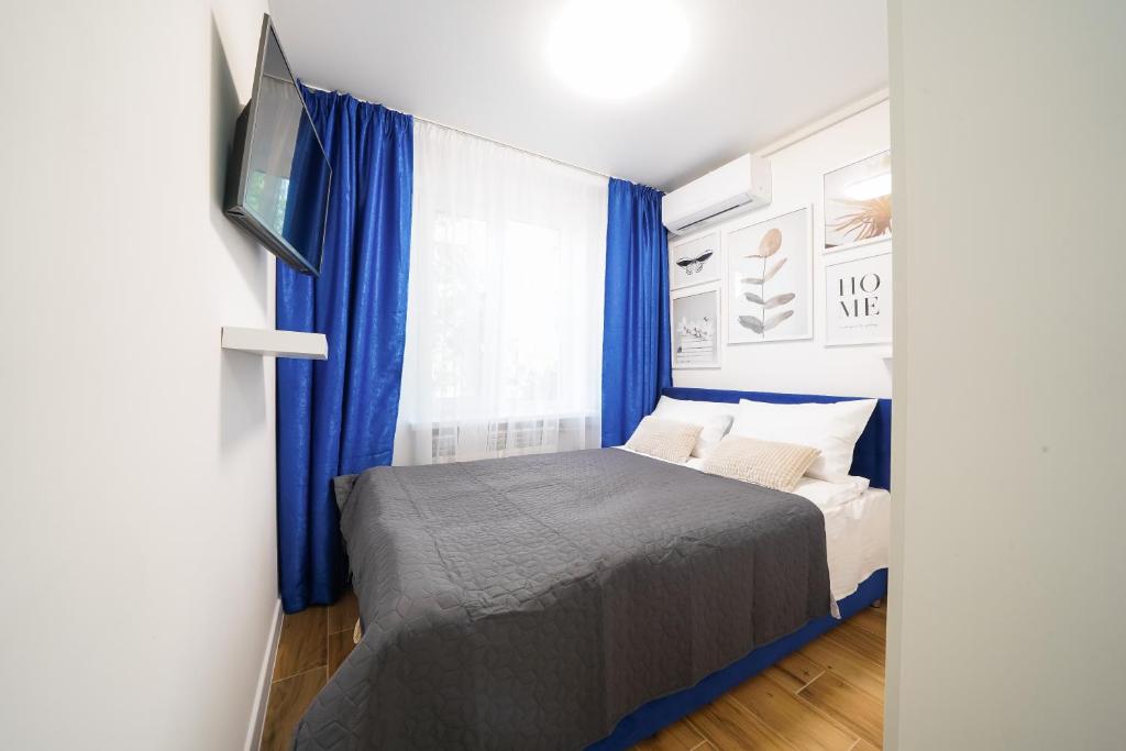 a bedroom with a bed with blue curtains and a tv at Апартаменти MYFREEDOM поруч із метро Чернігівська in Kyiv