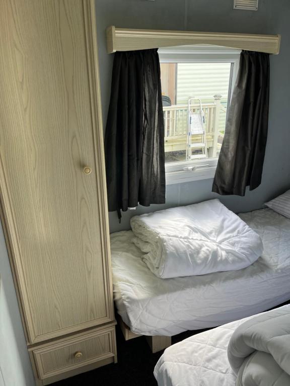a mirror in a room with two beds and a window at Colemans Caravans Golden Anchor Caravan Park in Chapel Saint Leonards