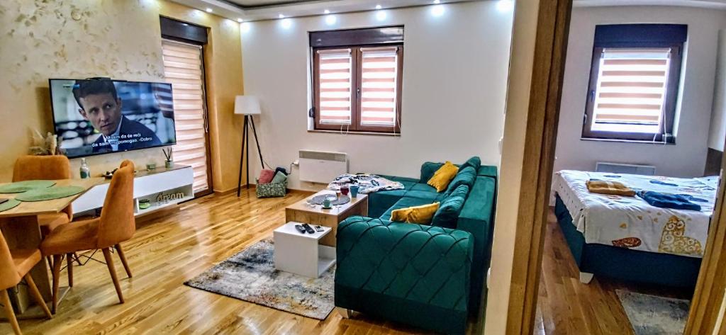 ein Wohnzimmer mit einem grünen Sofa und einem TV in der Unterkunft Green 21 LUX Wellness & Spa Zlatibor in Zlatibor