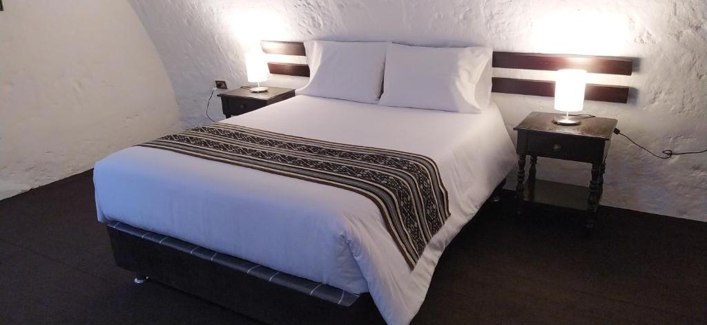 1 dormitorio con 1 cama blanca grande y 2 mesitas de noche en APARMENT SAMANA HOUSE AREQUIPA, en Arequipa