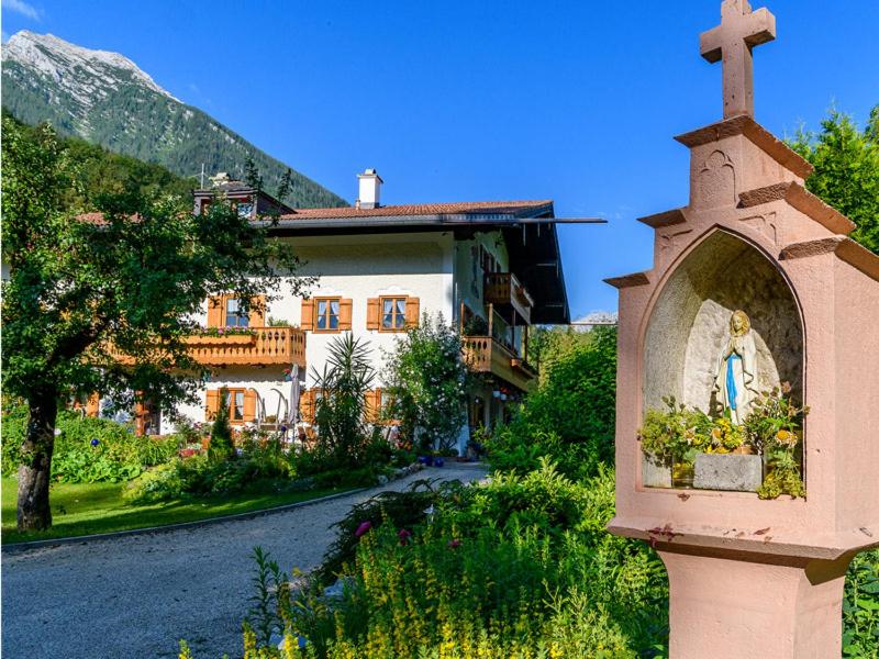 una chiesa con una croce di fronte a un edificio di Ferienwohnungen Neuhausenlehen a Ramsau