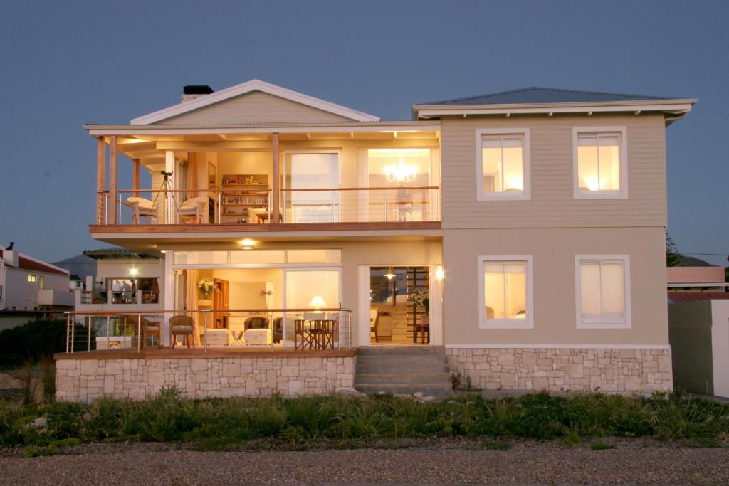 een groot wit huis met lichten aan bij 138 Marine Beachfront Guesthouse in Hermanus