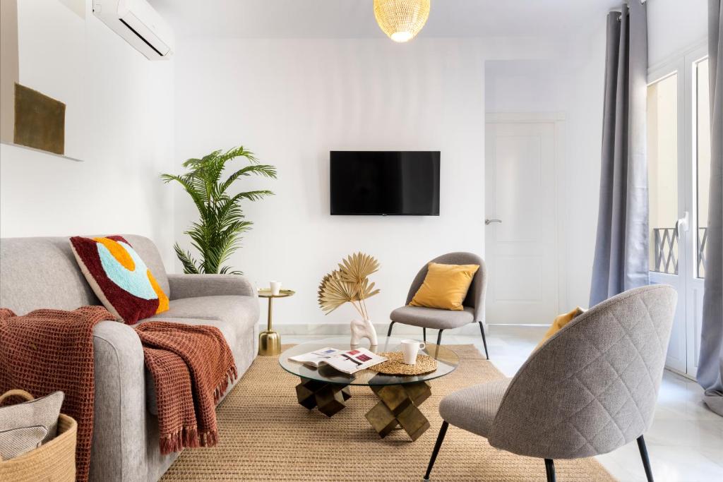塞維利亞的住宿－Suites Maestranza - Refinadores by Magno Apartments，客厅配有沙发、椅子和电视