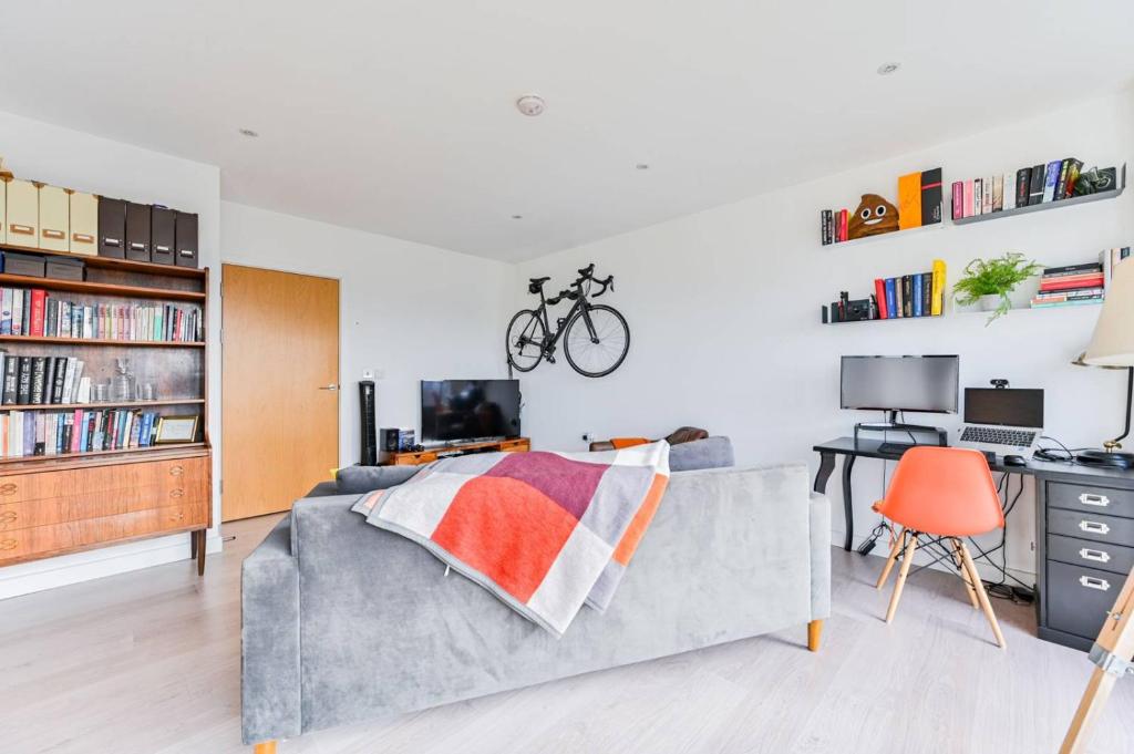 1 dormitorio con sofá y escritorio con bicicleta en 2-Bed Apartment only 15 mins from Central London, en Londres