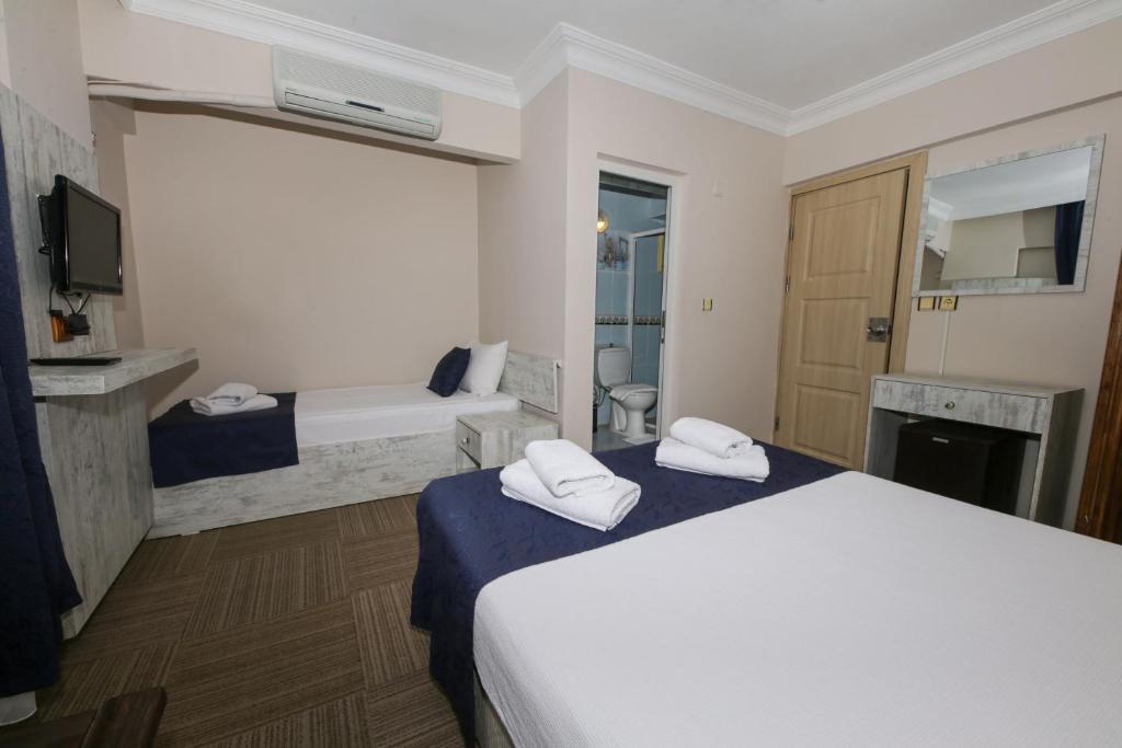 una camera d'albergo con letto bianco e TV di MELODİ BUTİK OTEL a Edremit