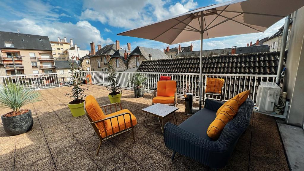 un patio con sillas y una sombrilla en el balcón en Accueillant T2 rénové clim centre ville terrasse en Brive-la-Gaillarde