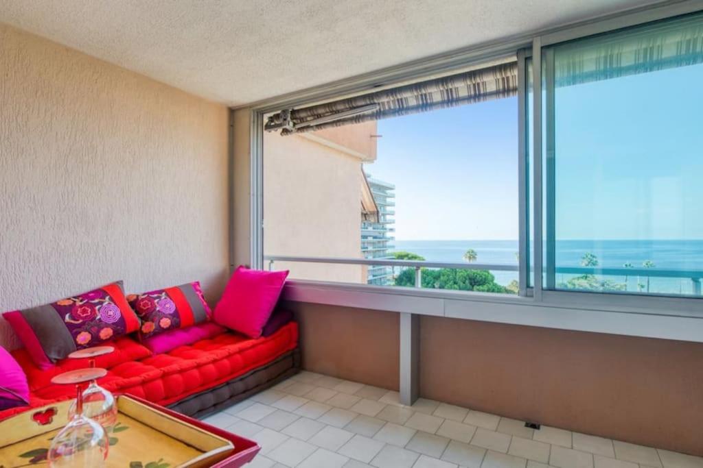 - un salon avec un canapé rouge et une grande fenêtre dans l'établissement Mer et Plage YourHostHelper 2 étoiles, à Cannes