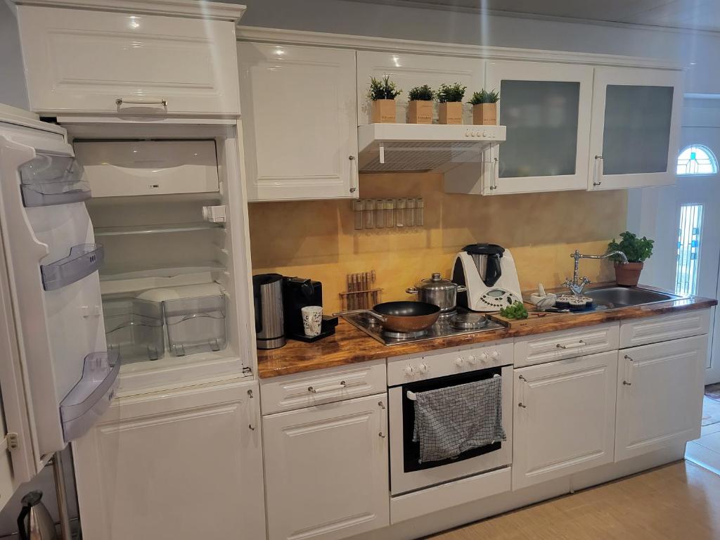 uma cozinha com armários brancos e um frigorífico branco em Ferienwohnung für 4 Personen mit schnellem WLAN, Glasfaser, TV Paket em Beilstein