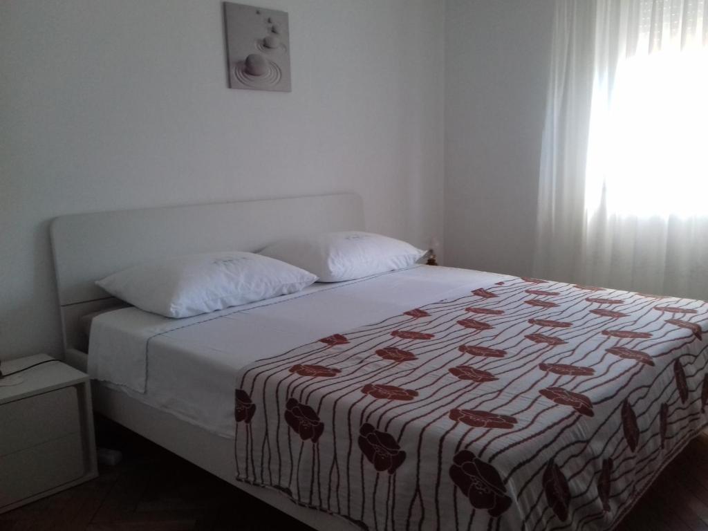 a bedroom with a bed with a blanket and a window at Apartment Dragan in Pula