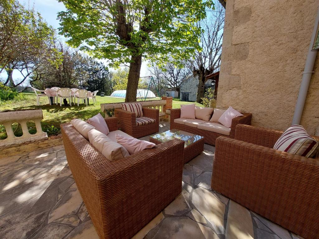 un patio con sillas y sofás de mimbre y un árbol en Maison de Vacances Tissendie, en Bourg-de-Visa