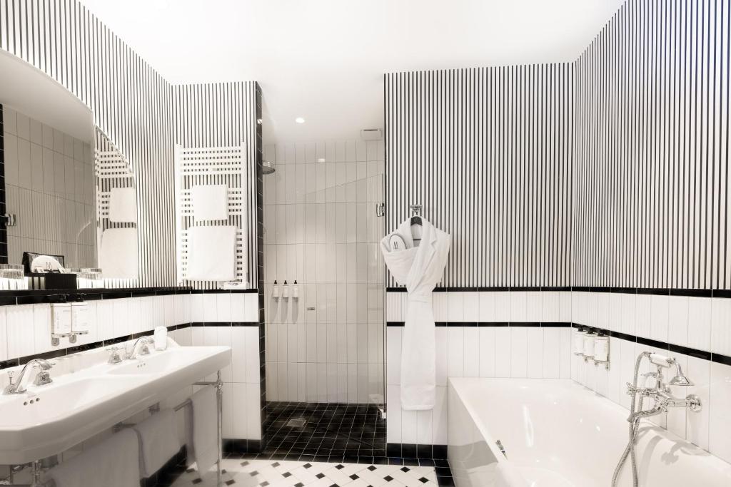 a black and white bathroom with two sinks and a bath tub at The 1932 Hotel & Spa Cap d'Antibes - MGallery Collection in Juan-les-Pins