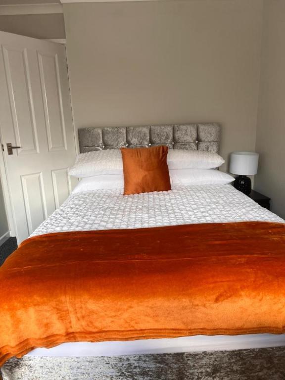 a bedroom with a large bed with an orange pillow at The Coral 66 Guest House Southampton in Southampton