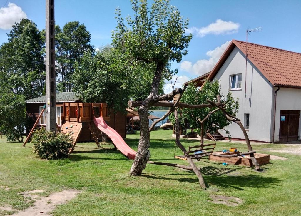 a playground in a yard next to a house at Owocowe Wakacje - Domek nad jeziorem in Mikołajki