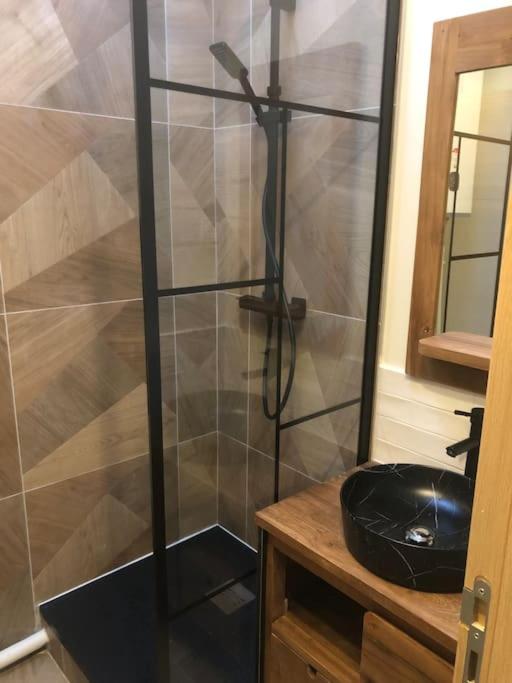 une douche avec une porte vitrée dans une salle de bain dans l'établissement Studio quartier Batignolles, à Paris