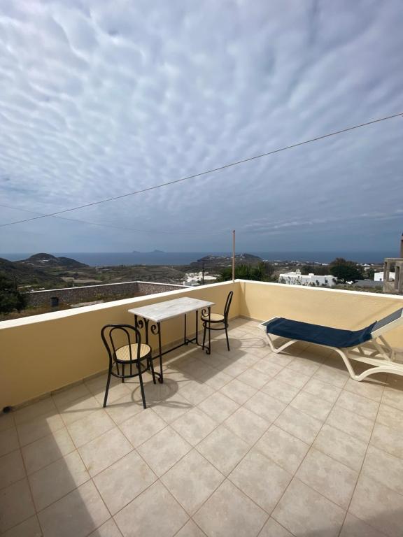 een patio met een tafel en stoelen op een dak bij AEOLOS Apartments in Akrotiri