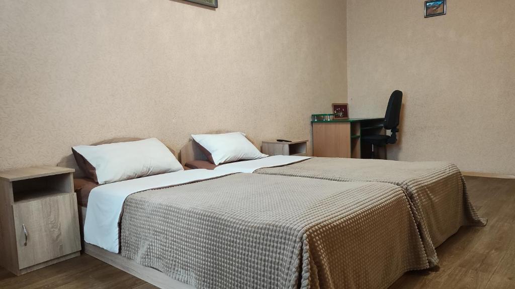 a bedroom with two beds with white sheets and a desk at Василя Стуса 10 City Rooms in Bila Tserkva