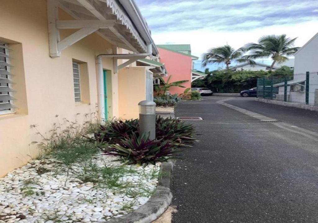 a street in front of a building with palm trees at Maison Agréable Familiale in Saint-François