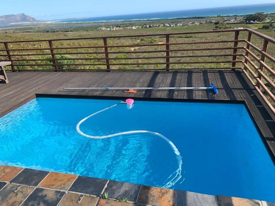 una piscina azul en una terraza con el océano en el fondo en Witteklip self-catering farm, en Kleinmond
