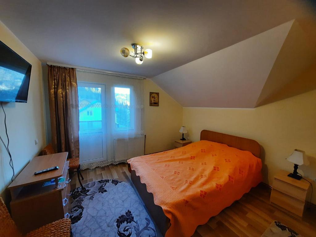 een slaapkamer met een bed, een bureau en een raam bij Casa Aurici Vatra Dornei in Vatra Dornei