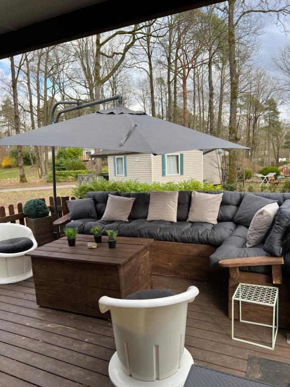 un canapé installé sur une terrasse avec un parasol dans l'établissement mobil home, à Mirgaudon