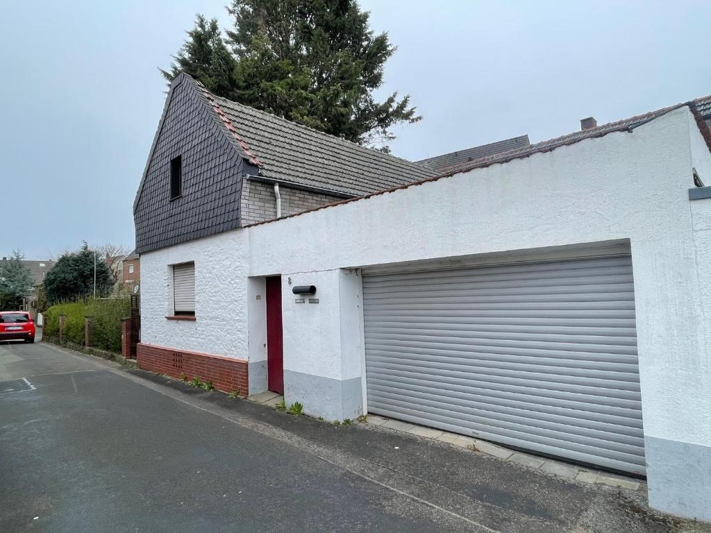 a white building with a garage door next to a street at Bollgarten Apartment 8 in Cologne