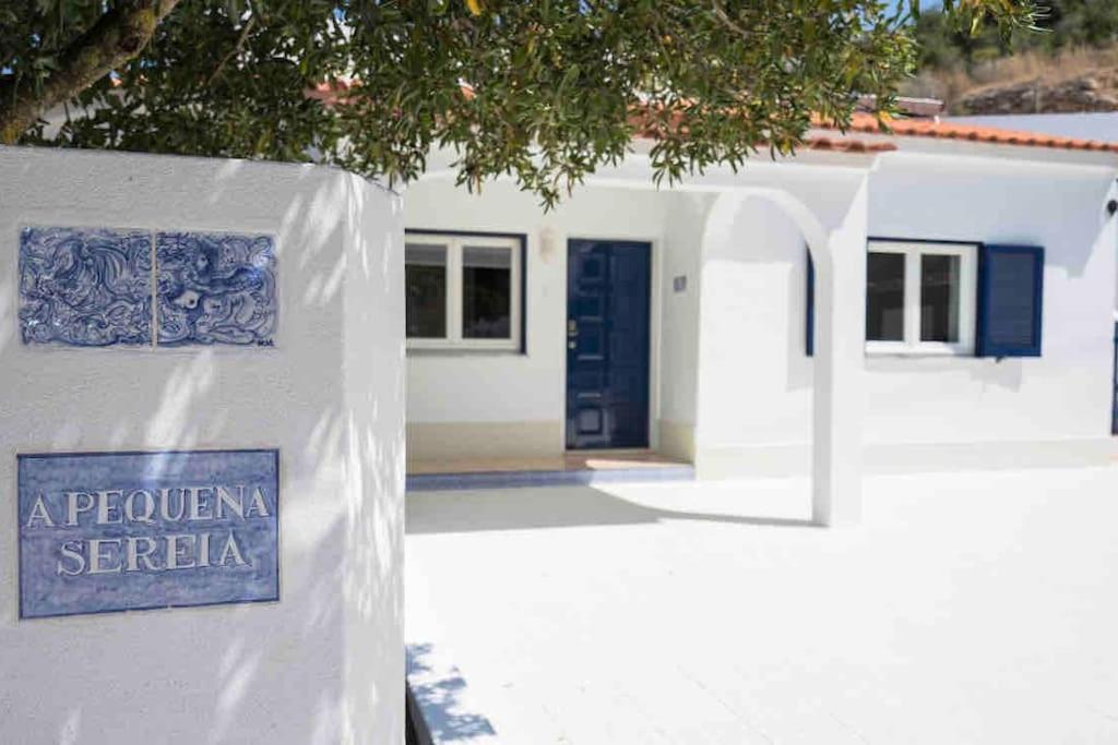 a sign in front of a house with a blue door at Casa a pequena sereia in Benagil with sea view in Carvoeiro