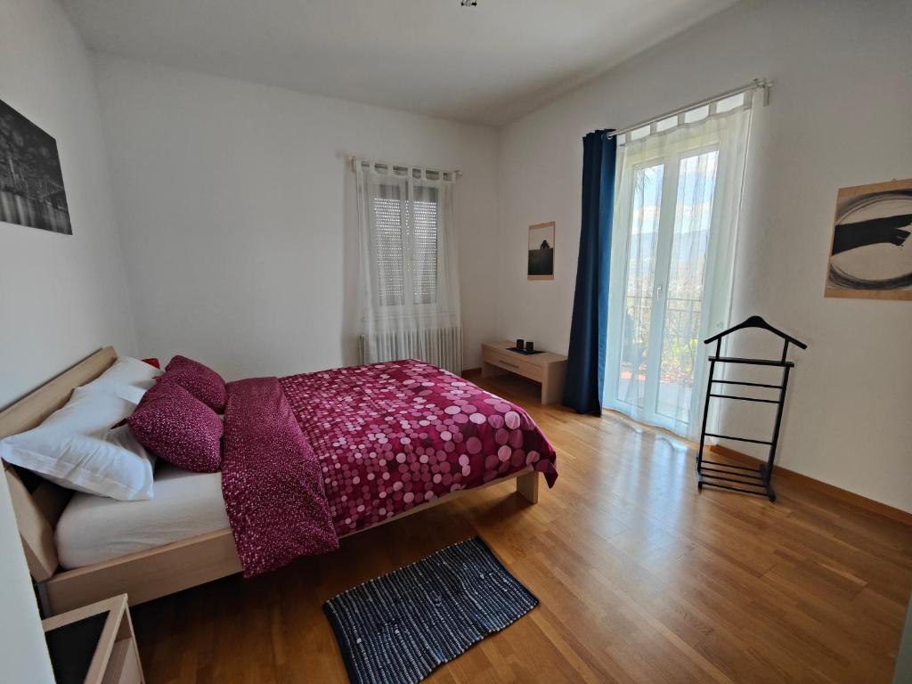 Casa le palme -Montagnola في Collina d'Oro: غرفة نوم بسرير ونافذة كبيرة
