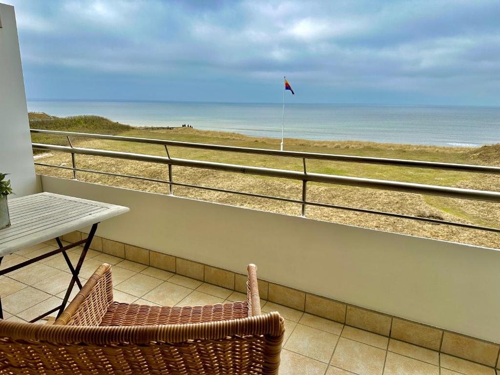 a balcony with a table and chairs and a view of the beach at KNYD'S am MEER in Wenningstedt