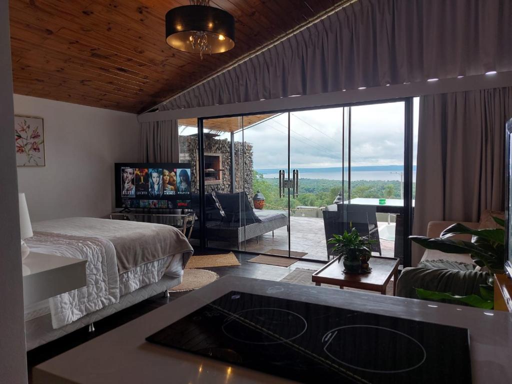 a bedroom with a bed and a living room with a view at Vista Lago Suites PY in Itauguá