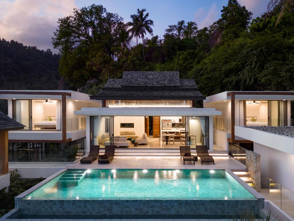 a villa with a swimming pool in front of a house at Samui Privacy Modern Luxury Seaview Natural Rainforest Infinity Pool Villa in Koh Samui 