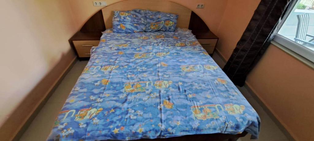 a bed in a small room with a blue bedspread at House by the sea in Shekvetili