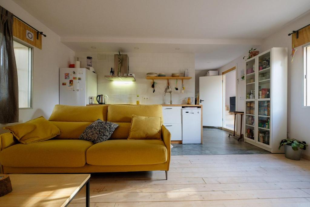 sala de estar con sofá amarillo y cocina en El apartamentito de Casa del Abuelo, en Isla Canela
