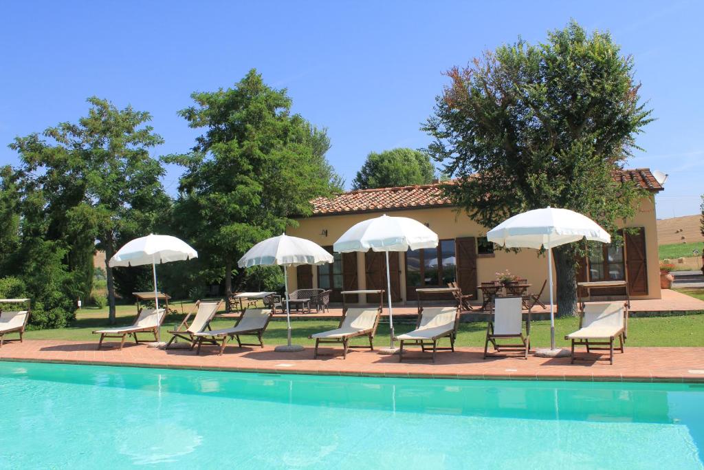 a group of chairs and umbrellas next to a pool at Agriturismo Piandimaggio in Pienza