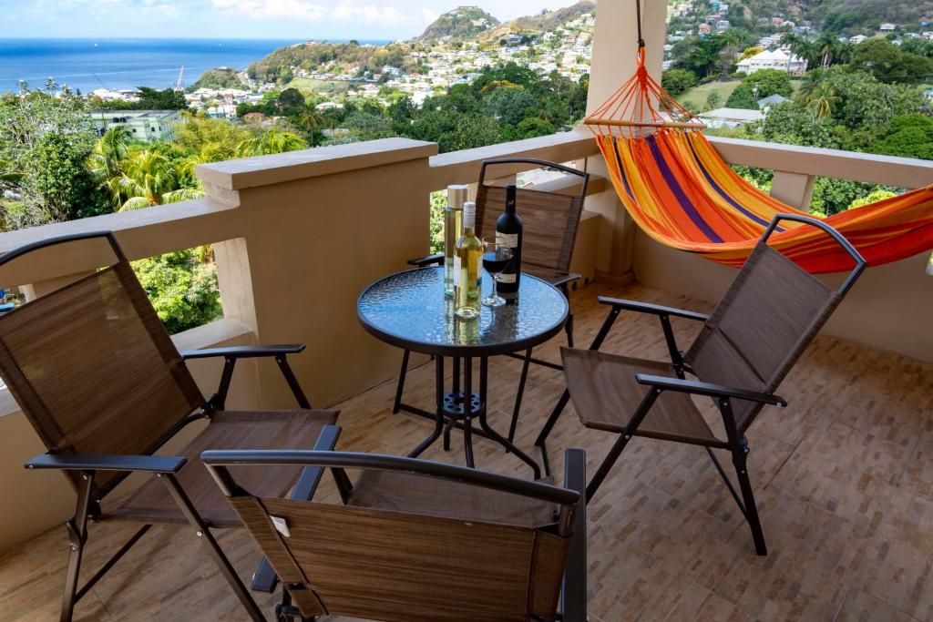 een balkon met een tafel en stoelen en een hangmat bij Royal Bliss Apartment Suites in Kingstown