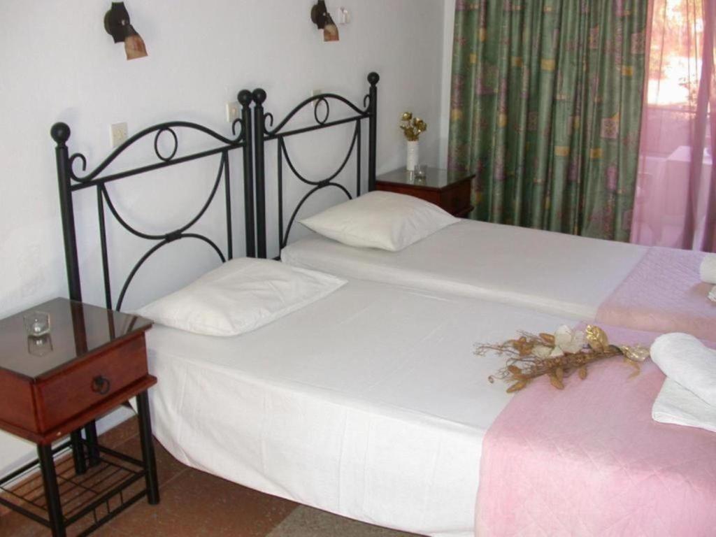 a bedroom with two beds and a table with a night stand at Yianna Apartments in Faliraki