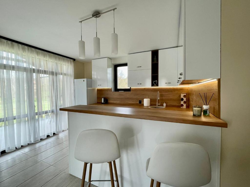 a kitchen with a counter and two stools in a room at Къща за гости ЕМ Парадайс in Tserova Koriya