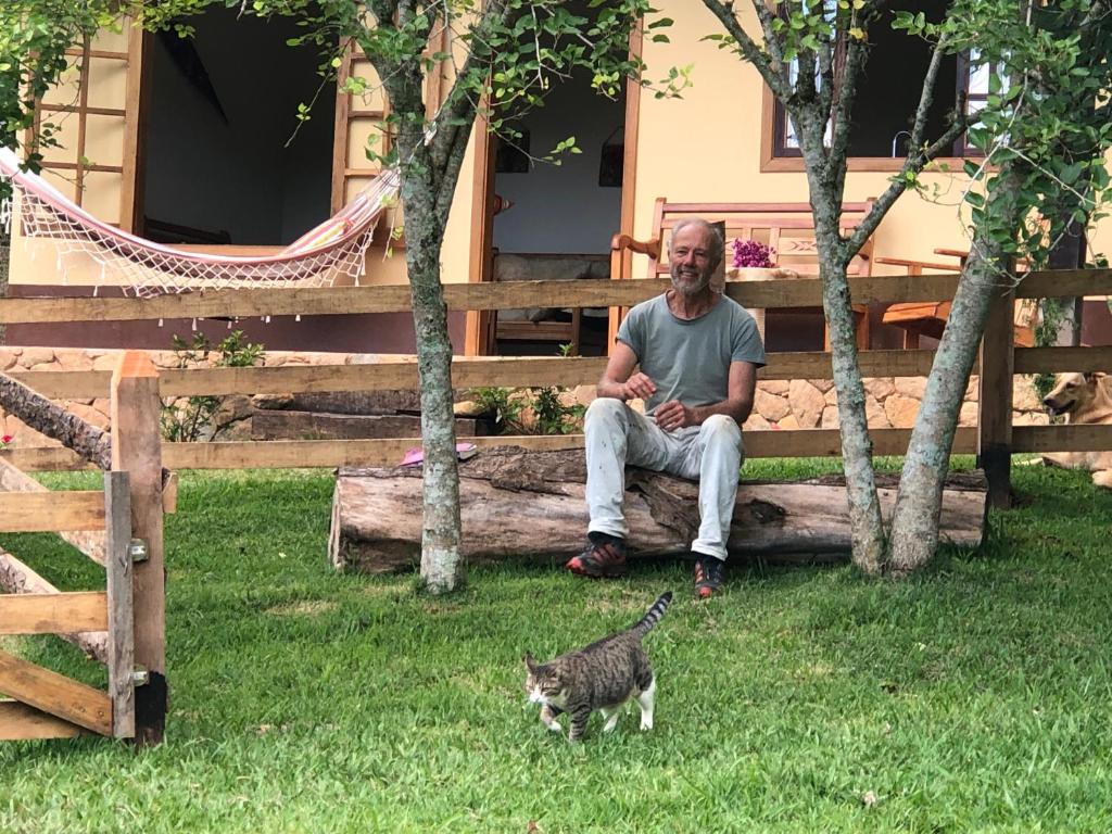 a man sitting on a bench next to a cat at Sitio Eco Friends - Perfeita para Casal e Família! in São Bento do Sapucaí