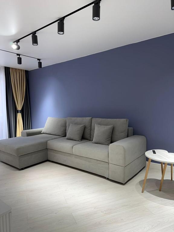 a living room with a couch and a blue wall at Nursultana Nazarbaeva 20 Str by Slissenko Inn in Pavlodar