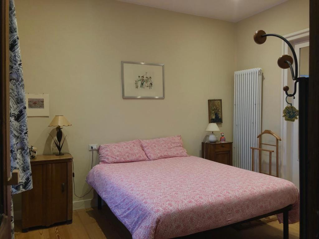 a bedroom with a bed with a pink blanket at casa silvio pellico in Cuneo