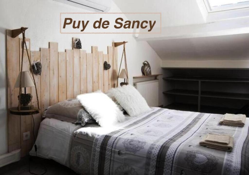 a bedroom with a large bed with a wooden headboard at Logements Chaîne des Puys avec garages attenants in Clermont-Ferrand