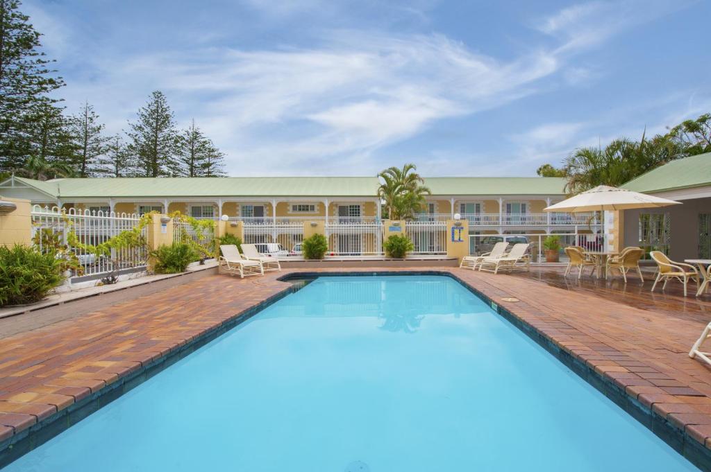 a swimming pool in front of a resort building at Wollongbar Motel in Byron Bay