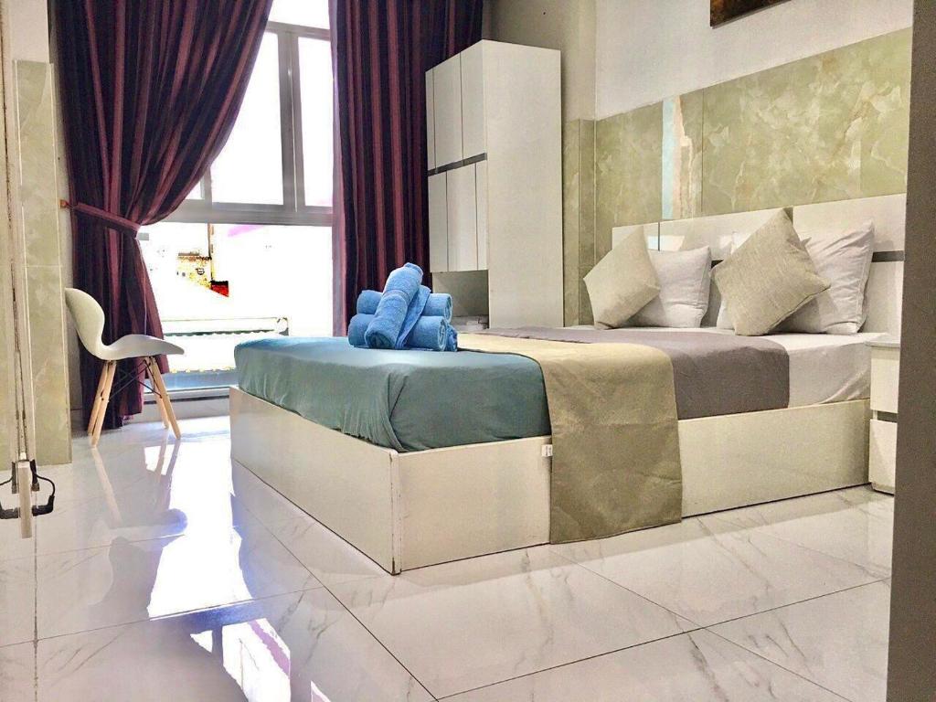 a bedroom with a large bed with a blue chair at SaiGon CoZy Hotel "241 Pham Ngu Lao Street'' in Ho Chi Minh City