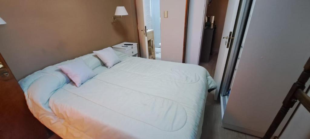 a small bedroom with a white bed with two pillows at La Marta in Ciudad Lujan de Cuyo