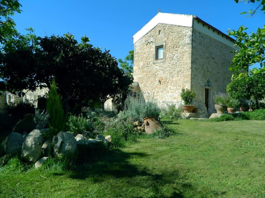 una casa de piedra con un patio con rocas y un edificio en Villa Venetico stone retreat with garden, en Faneroméni