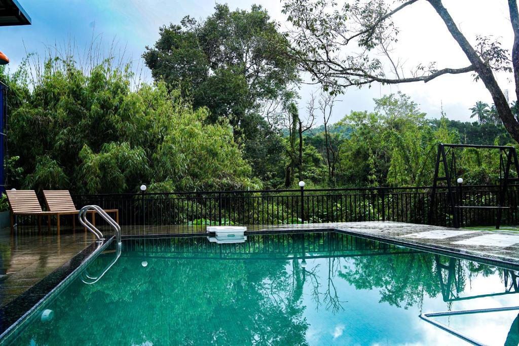 une piscine avec une clôture noire et des arbres dans l'établissement Caravan holiday homes Vythiri, à Vythiri