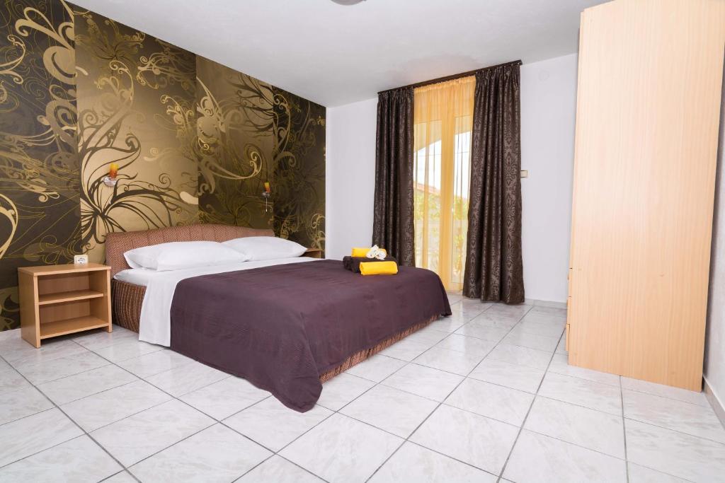 sypialnia z łóżkiem i dużym oknem w obiekcie Apartments Ilak w Trogirze